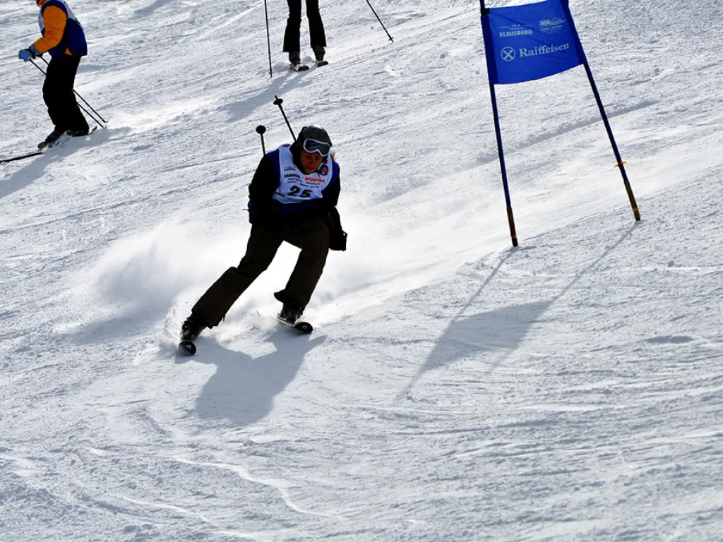 Snowboarder zieht eine Kurve, oben warten weitere Startende.